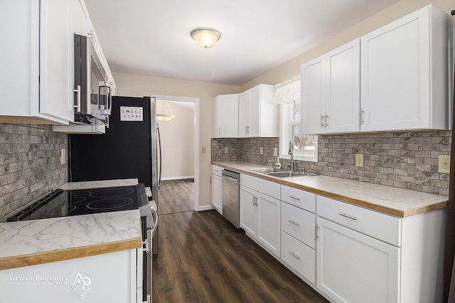 kitchen featuring stainless steel appliances, a sink, decorative backsplash, white cabinets, and light countertops