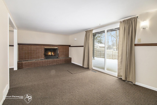 unfurnished living room with a brick fireplace and dark colored carpet