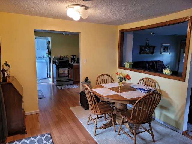 dining room with a textured ceiling, light hardwood / wood-style flooring, and washer / clothes dryer