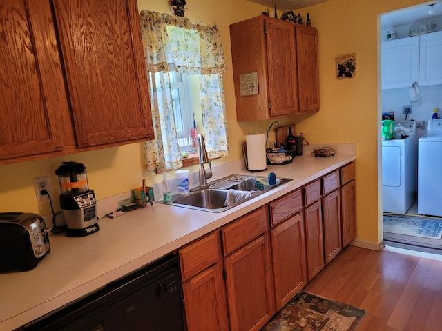 kitchen with light hardwood / wood-style floors, sink, black dishwasher, and independent washer and dryer