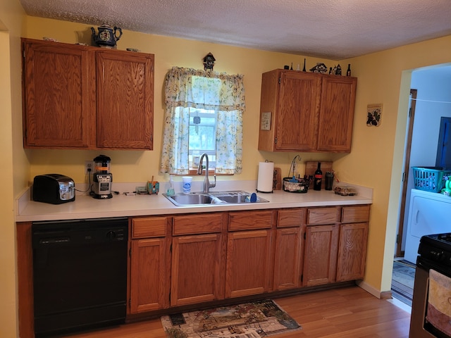 kitchen with dishwasher, stainless steel stove, sink, light wood-type flooring, and a textured ceiling