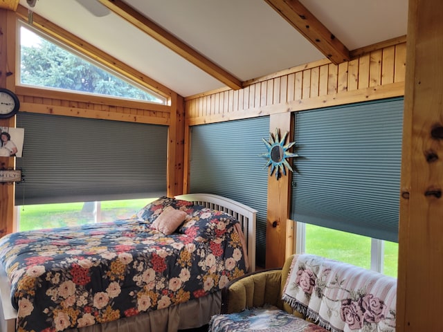 bedroom with multiple windows, wood walls, and lofted ceiling with beams