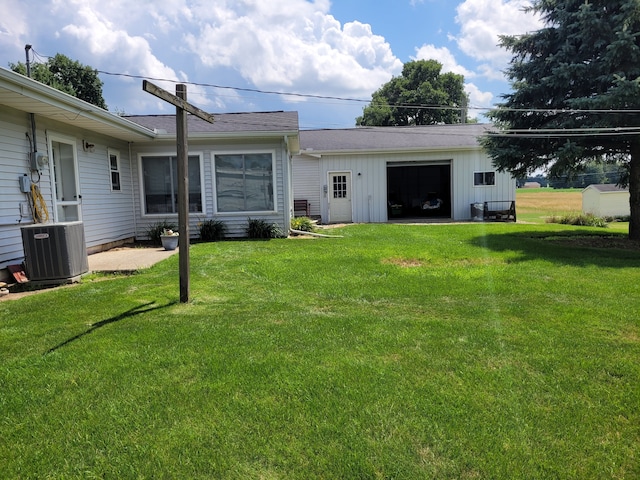 rear view of house featuring a garage, cooling unit, and a lawn