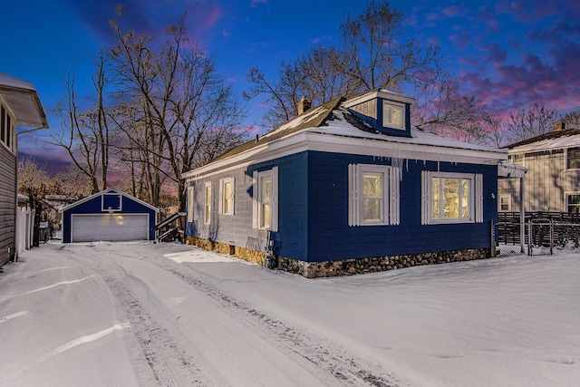 snow covered property featuring a garage and an outdoor structure