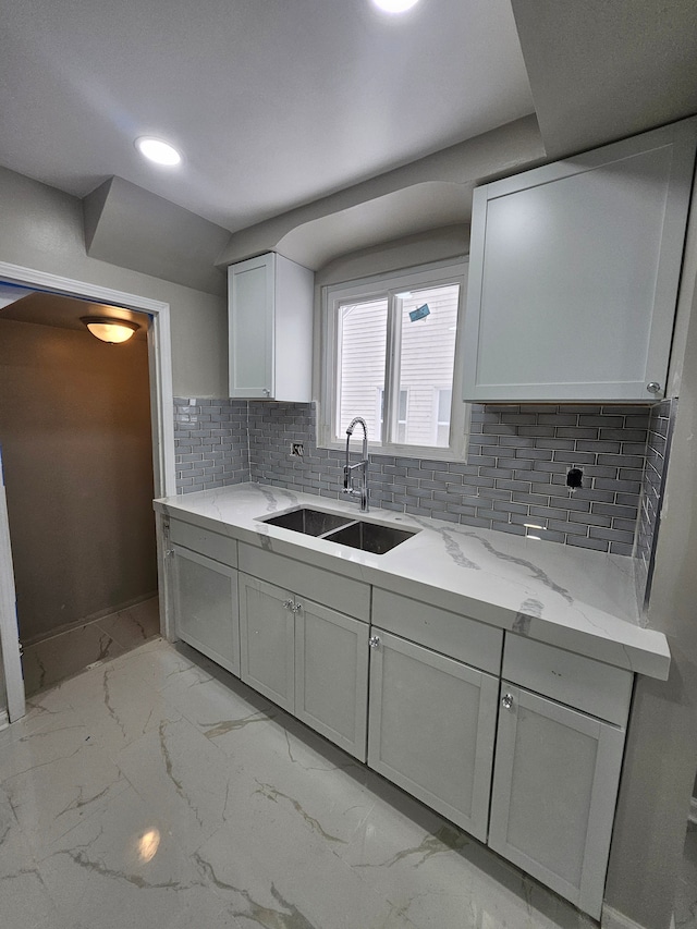 kitchen with light stone counters, backsplash, and sink