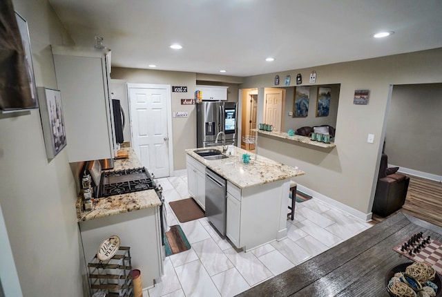 kitchen featuring white cabinets, stainless steel appliances, an island with sink, a breakfast bar, and sink