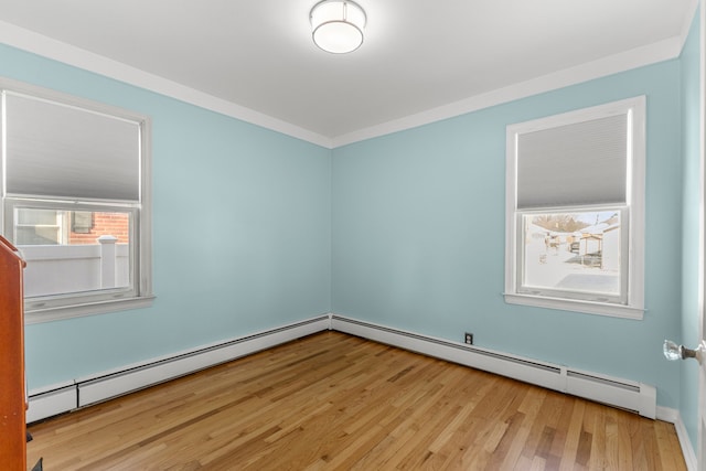 spare room featuring ornamental molding, a baseboard radiator, and light hardwood / wood-style flooring