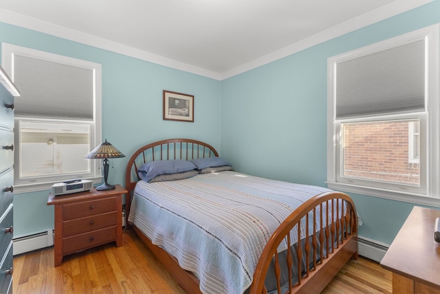 bedroom featuring a baseboard heating unit, ornamental molding, and light hardwood / wood-style floors