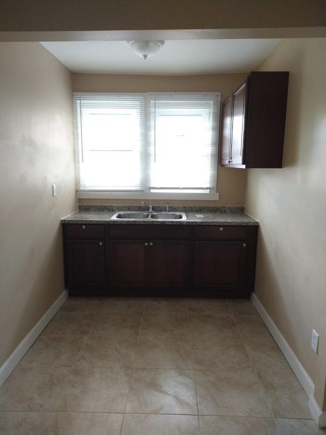 kitchen with sink, light tile patterned floors, and dark brown cabinets