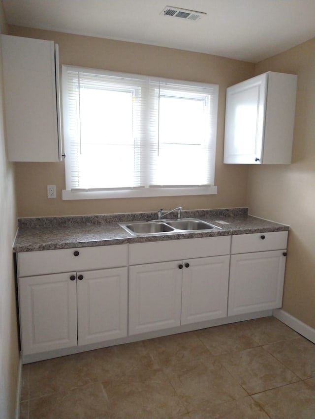 kitchen with sink, white cabinets, and light tile patterned flooring