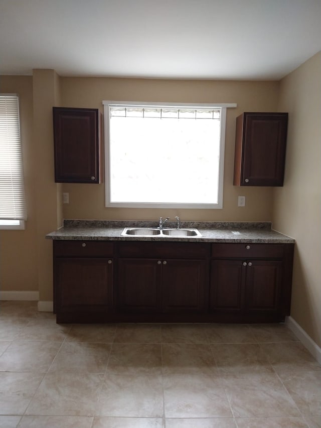 kitchen featuring sink, light tile patterned floors, and dark brown cabinetry