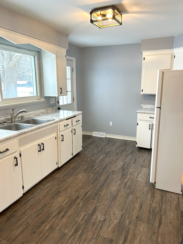 kitchen with white refrigerator, dark hardwood / wood-style flooring, white cabinets, and sink