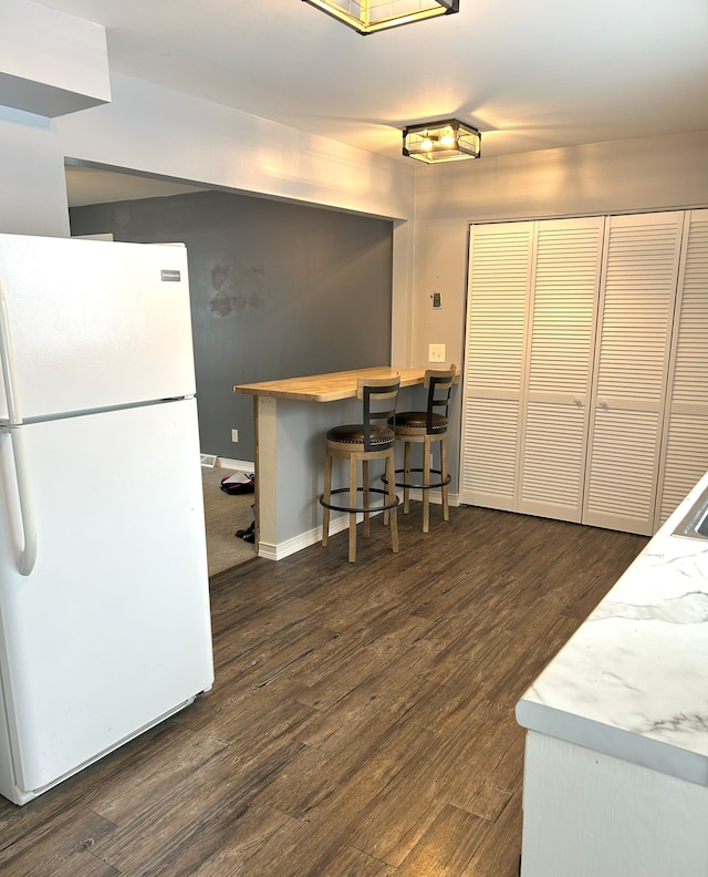 kitchen with white refrigerator and dark hardwood / wood-style flooring