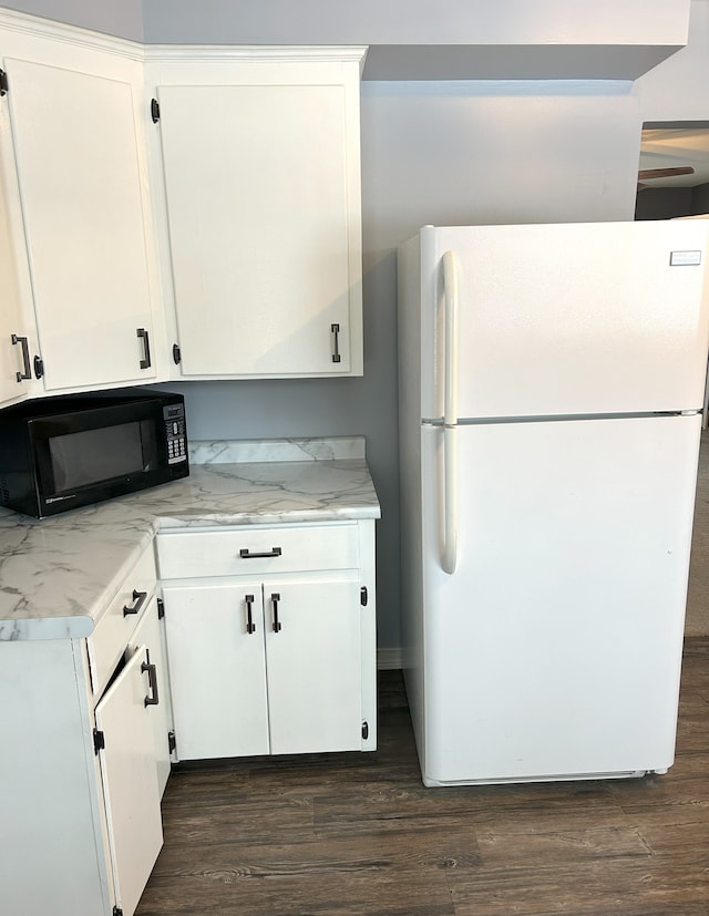 kitchen with white refrigerator, white cabinets, and light stone countertops