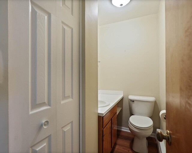 bathroom with toilet, hardwood / wood-style flooring, and vanity