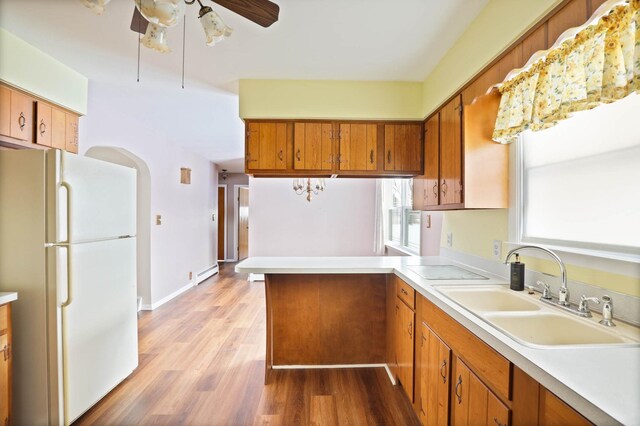 kitchen featuring white refrigerator, sink, ceiling fan, light wood-type flooring, and baseboard heating