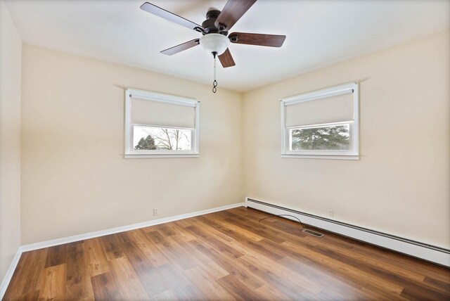 unfurnished room featuring ceiling fan, hardwood / wood-style floors, plenty of natural light, and a baseboard heating unit