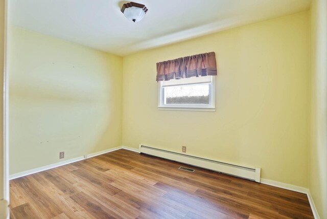 9800 Gera Rd, Birch Run, MI 48415 - spare room featuring a baseboard heating unit, wood finished floors, and baseboards