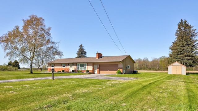 9800 Gera Rd, Birch Run, MI 48415 - single story home with a storage unit, asphalt driveway, a garage, a front lawn, and a chimney