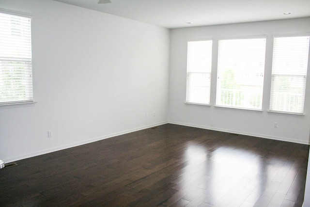 unfurnished room with a healthy amount of sunlight and dark hardwood / wood-style flooring