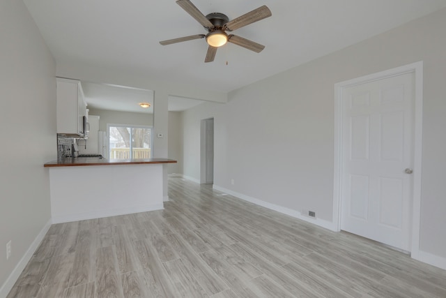 unfurnished living room featuring ceiling fan and light wood-type flooring