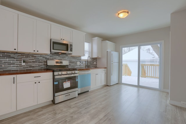 kitchen featuring appliances with stainless steel finishes, sink, white cabinets, backsplash, and light hardwood / wood-style floors