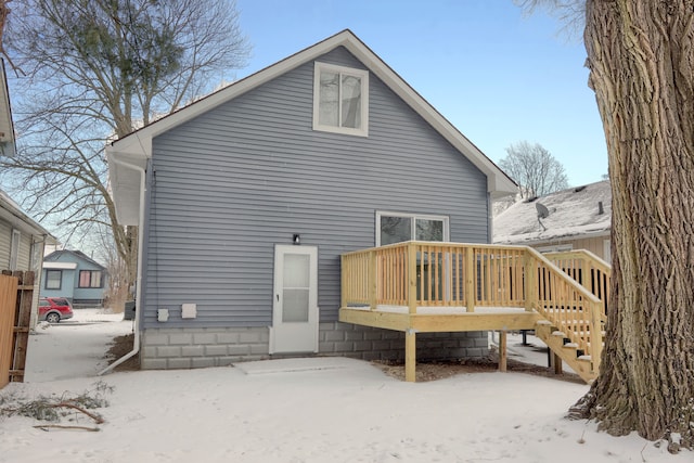 snow covered back of property featuring a wooden deck