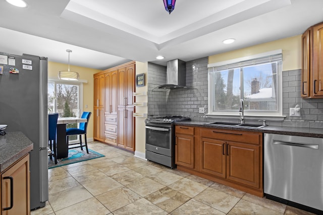 kitchen featuring sink, wall chimney exhaust hood, backsplash, hanging light fixtures, and appliances with stainless steel finishes