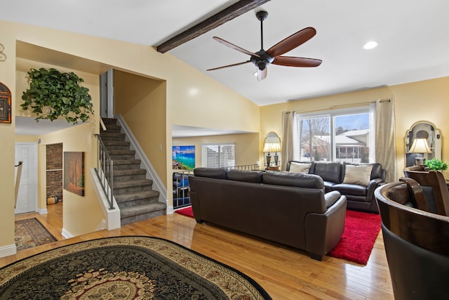 living room with ceiling fan, light wood-type flooring, and vaulted ceiling with beams