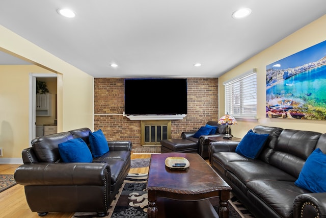 living room featuring brick wall, a fireplace, and hardwood / wood-style flooring