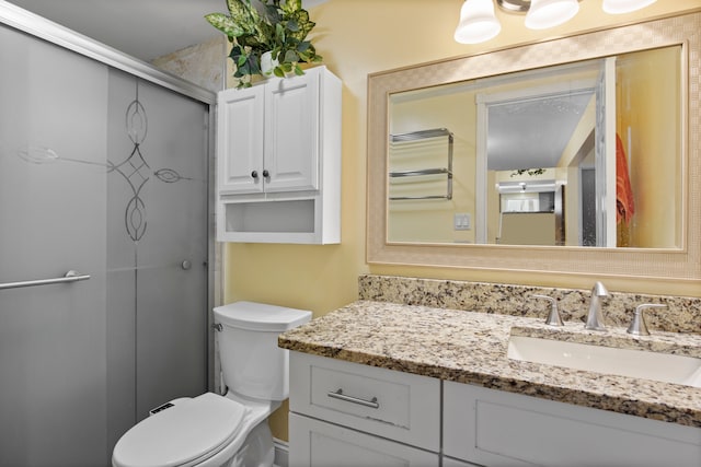 bathroom featuring toilet, vanity, and a shower with shower door