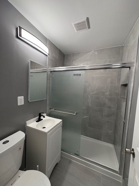 bathroom featuring toilet, tile patterned floors, walk in shower, and vanity