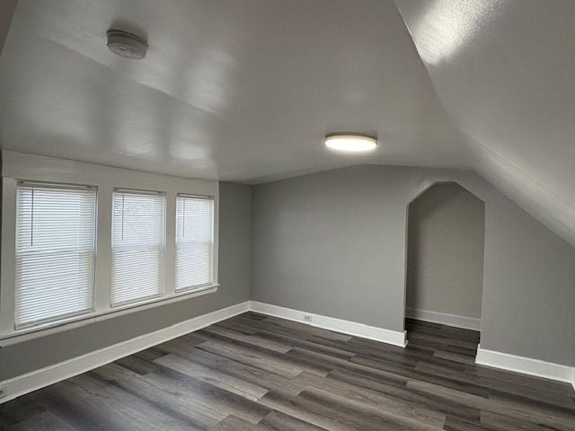 bonus room with vaulted ceiling and dark wood-type flooring