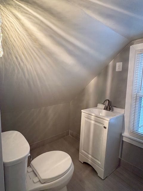 bathroom featuring toilet, vaulted ceiling, hardwood / wood-style floors, and vanity