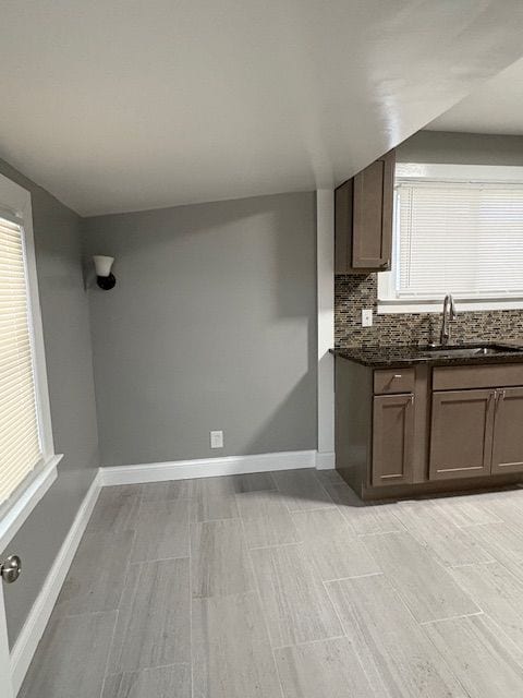 kitchen featuring sink, decorative backsplash, and dark stone counters