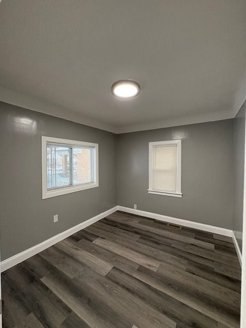 spare room featuring ornamental molding and dark wood-type flooring