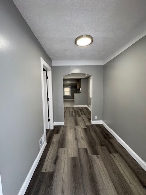 corridor featuring dark wood-type flooring and a textured ceiling