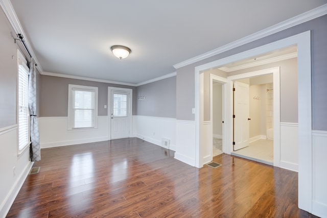 spare room featuring dark hardwood / wood-style flooring, ornamental molding, and a wealth of natural light