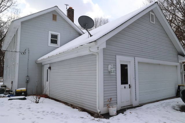 snow covered back of property with a garage