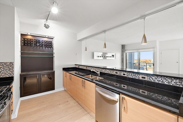 kitchen featuring track lighting, decorative light fixtures, stainless steel appliances, tasteful backsplash, and sink