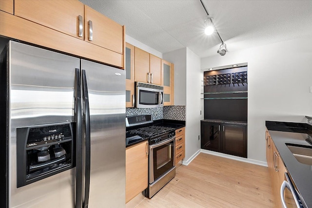 kitchen with tasteful backsplash, light hardwood / wood-style flooring, a textured ceiling, track lighting, and stainless steel appliances