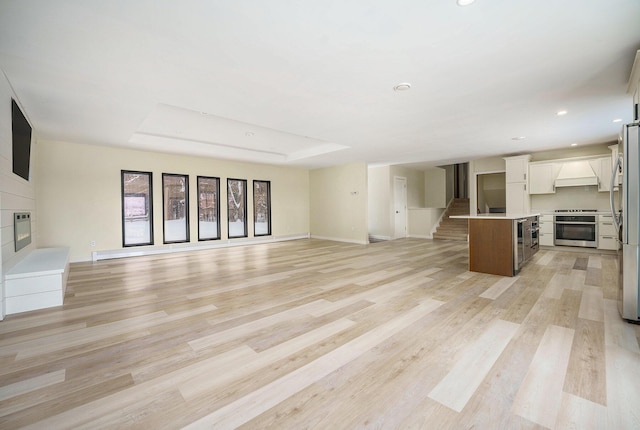 unfurnished living room featuring light hardwood / wood-style flooring and a tray ceiling