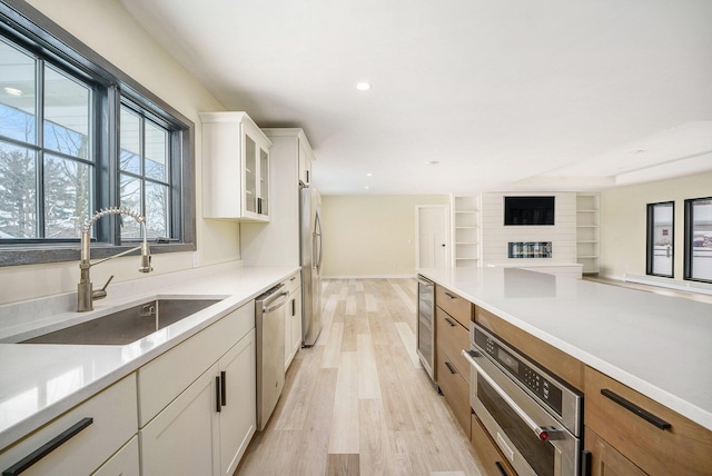 kitchen with light hardwood / wood-style flooring, wine cooler, white cabinetry, appliances with stainless steel finishes, and sink