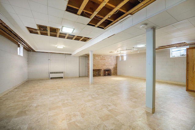 basement featuring a brick fireplace and radiator heating unit