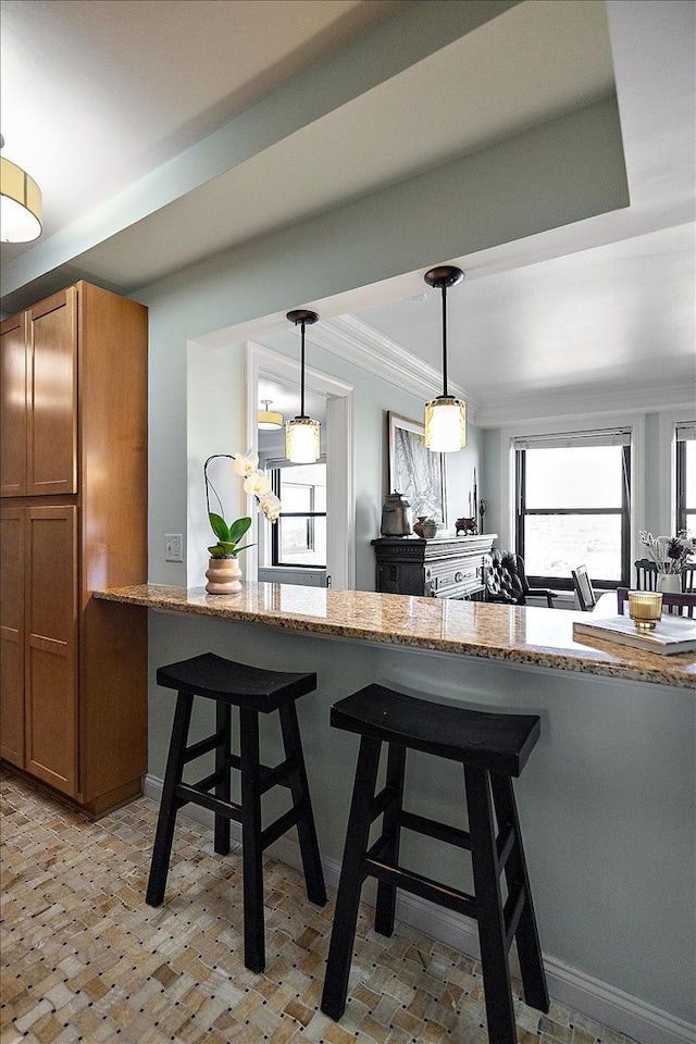 kitchen with light stone countertops, decorative light fixtures, a kitchen breakfast bar, kitchen peninsula, and crown molding