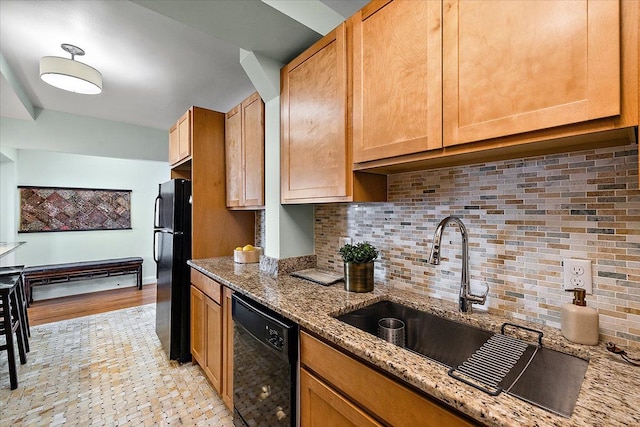 kitchen featuring light stone countertops, backsplash, black appliances, and sink