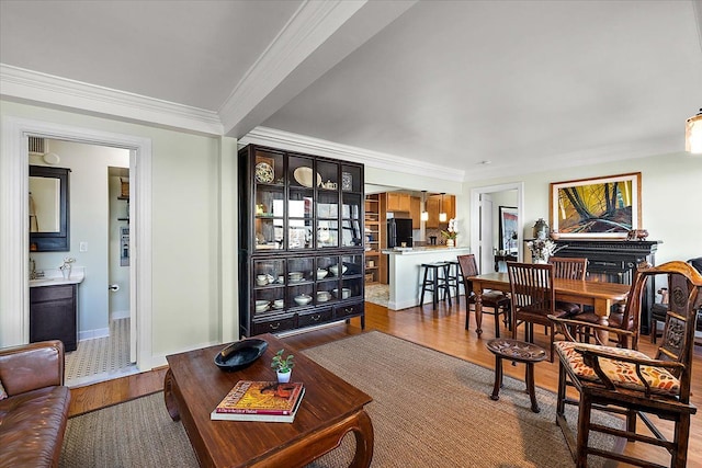 living room featuring beamed ceiling, ornamental molding, and hardwood / wood-style floors