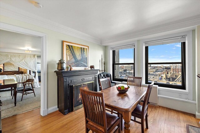 dining room with crown molding and light hardwood / wood-style flooring