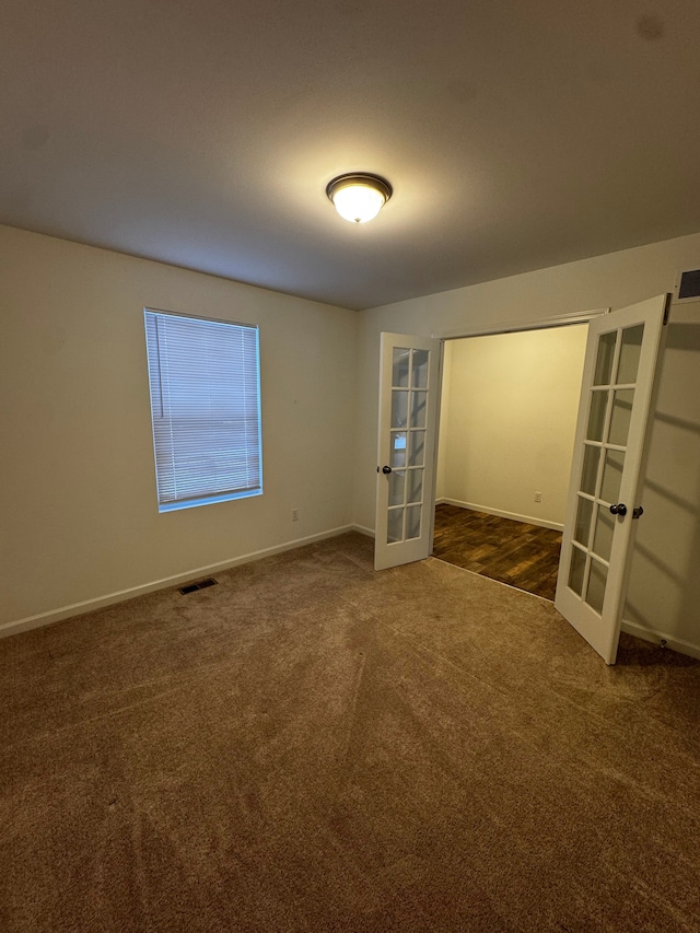 carpeted spare room featuring french doors