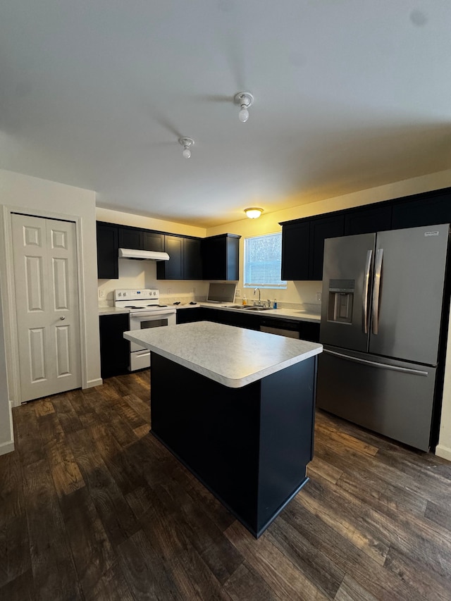 kitchen featuring dark wood-type flooring, appliances with stainless steel finishes, sink, and a center island